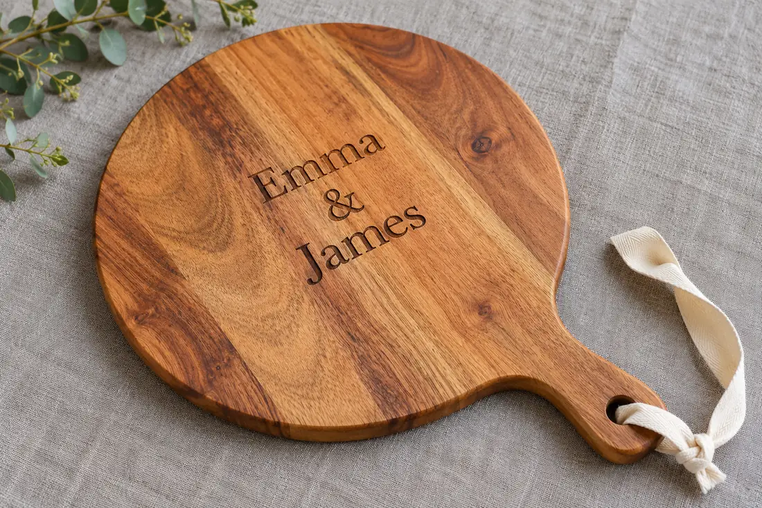 Round wooden charcuterie board engraved with Emma and James